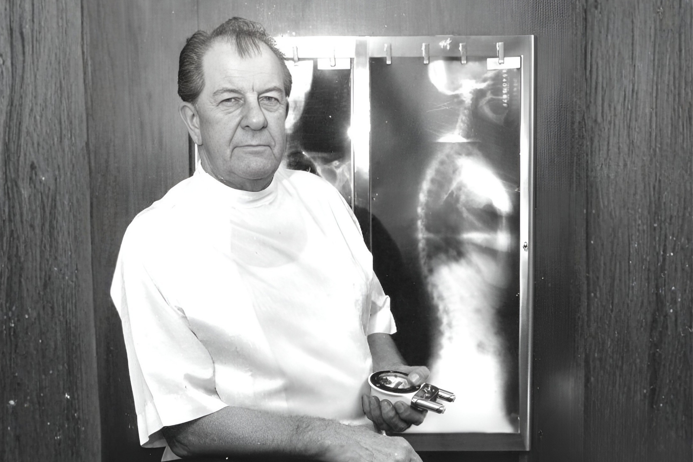 Dr. Gonstead with the instrument he designed, beside full spine films